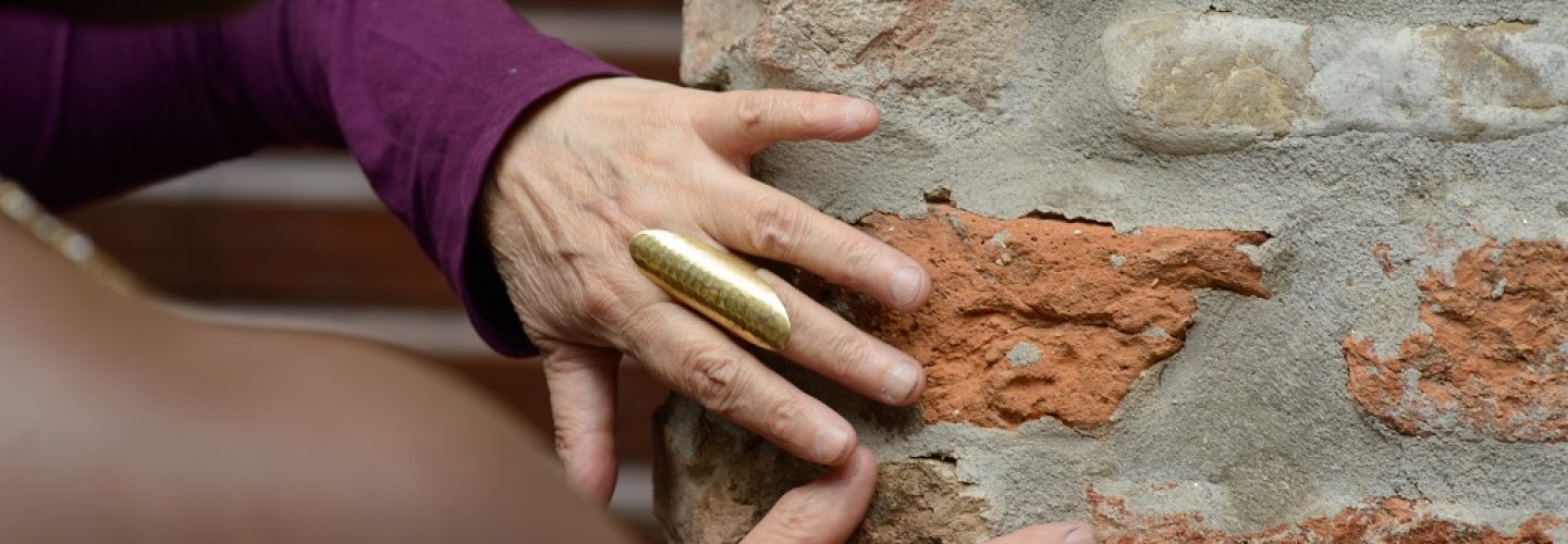 Closeup image capturing a person's hands gently touching the textured surface of an old, weathered brick wall