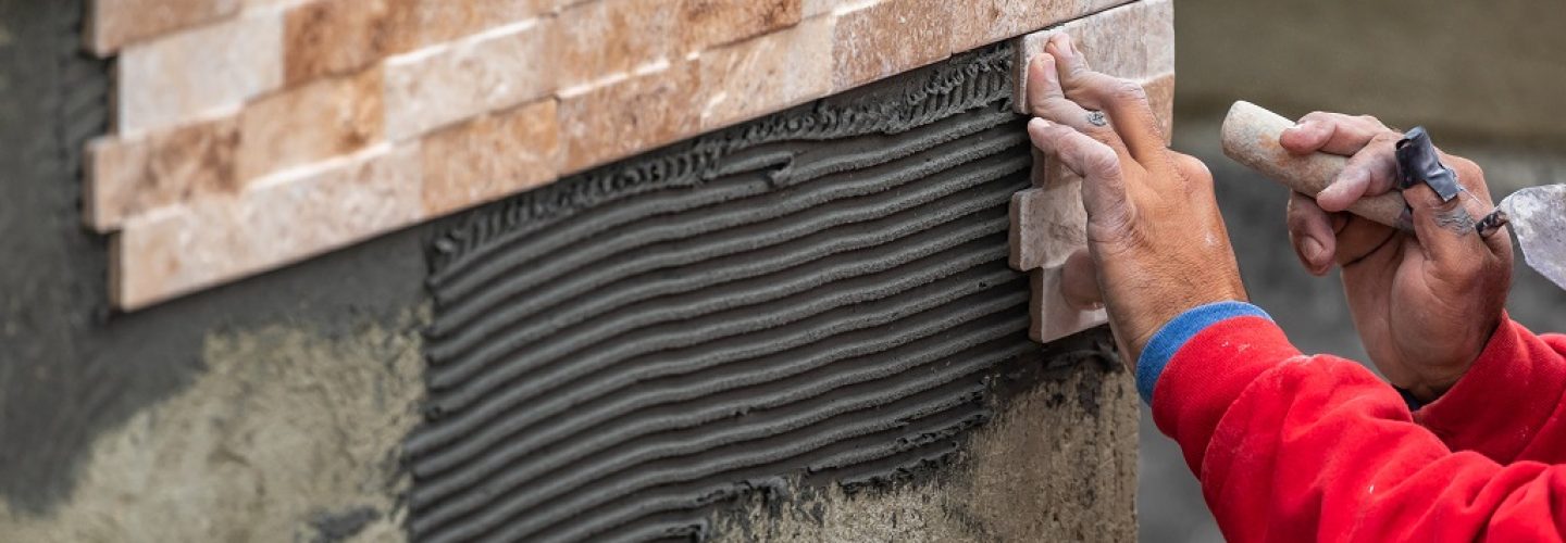 Worker Installing Wall Tile at Construction Site.